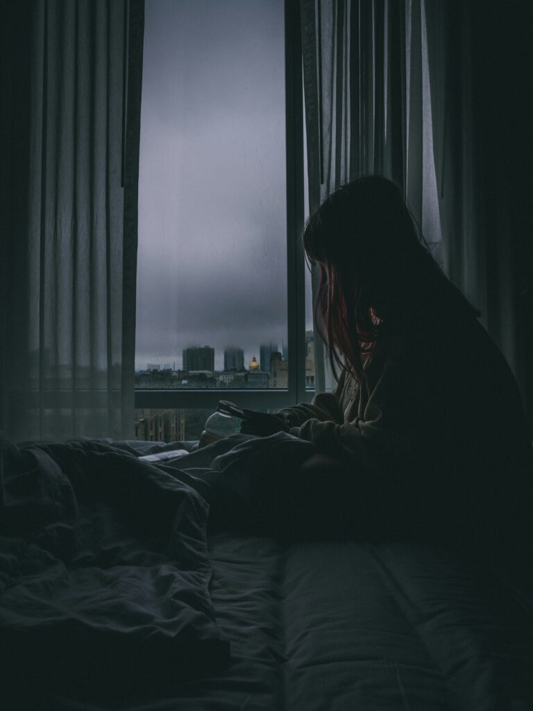 Woman looking lonely by a dark window